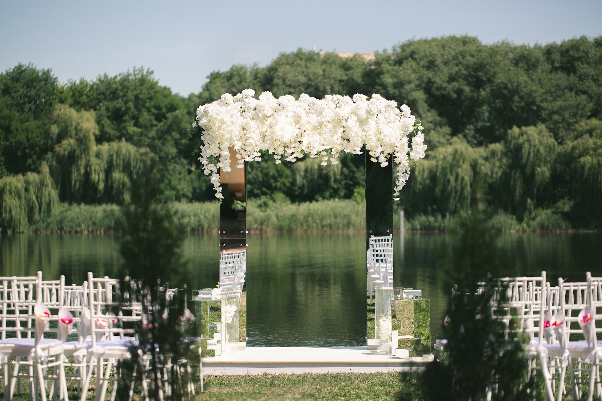 White mirrored wedding arch decorated with white flowers. The concept of an outdoor wedding ceremony