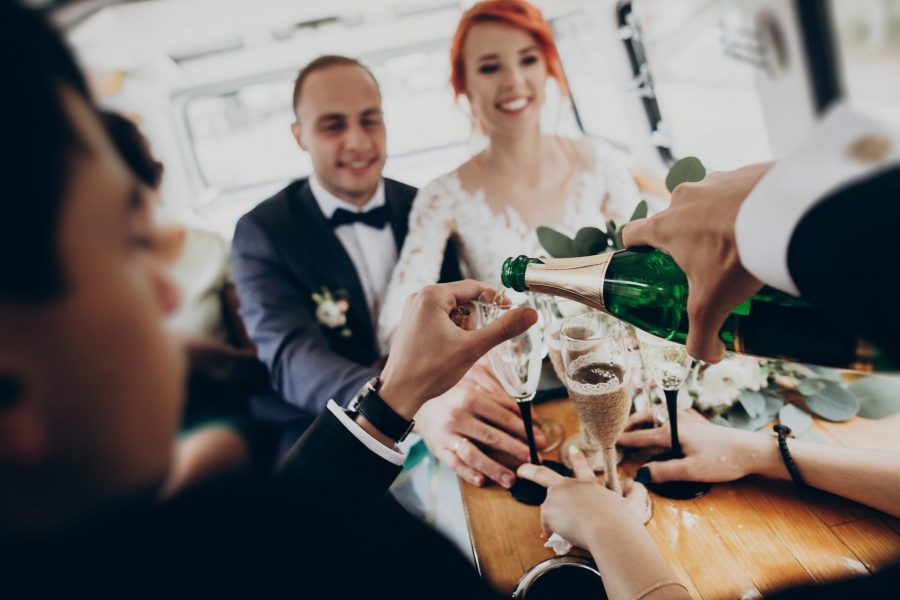 Stylish happy bride and groom toasting with glasses of champagne and having fun