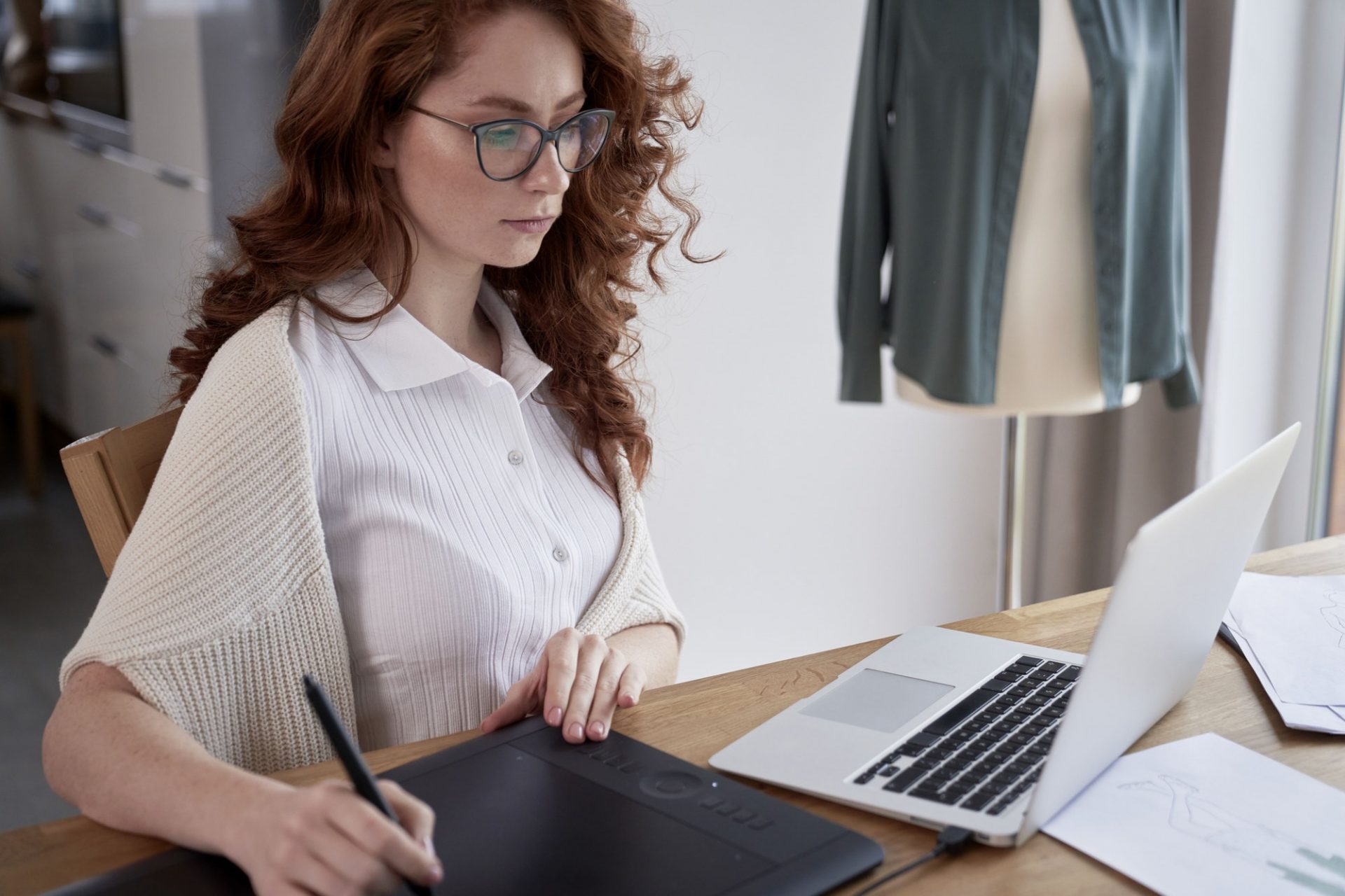 Young adult woman using laptop and designing a dress