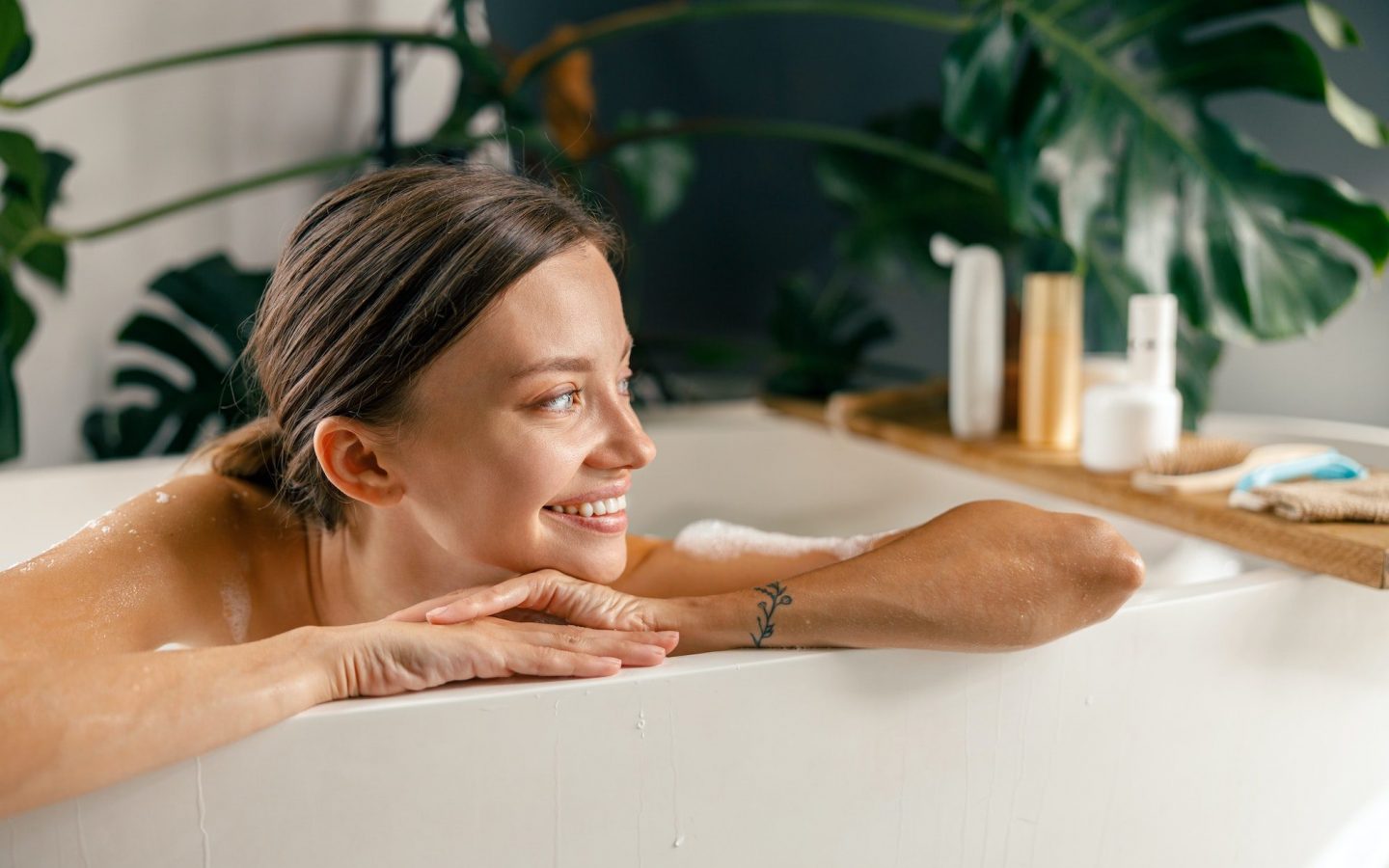 Portrait of happy young woman smiling aside while resting in bathtub at luxury spa resort