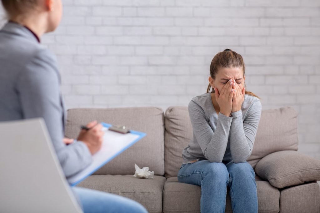 Mental health and psychological help concept. Young woman with depression on counseling session with