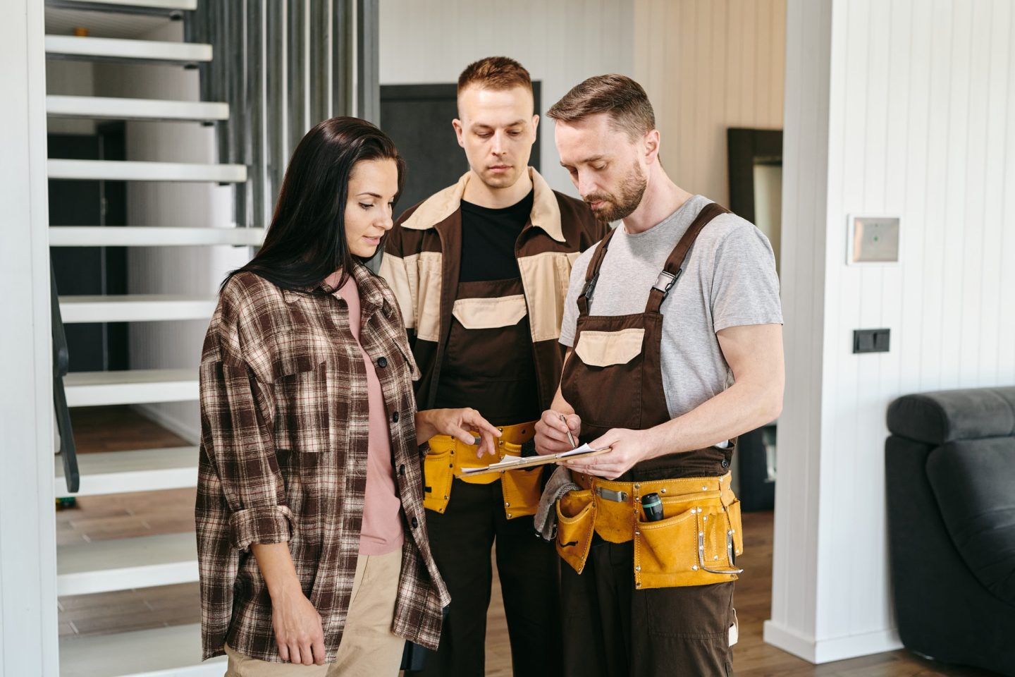 Two plumbers showing young woman where to put signature