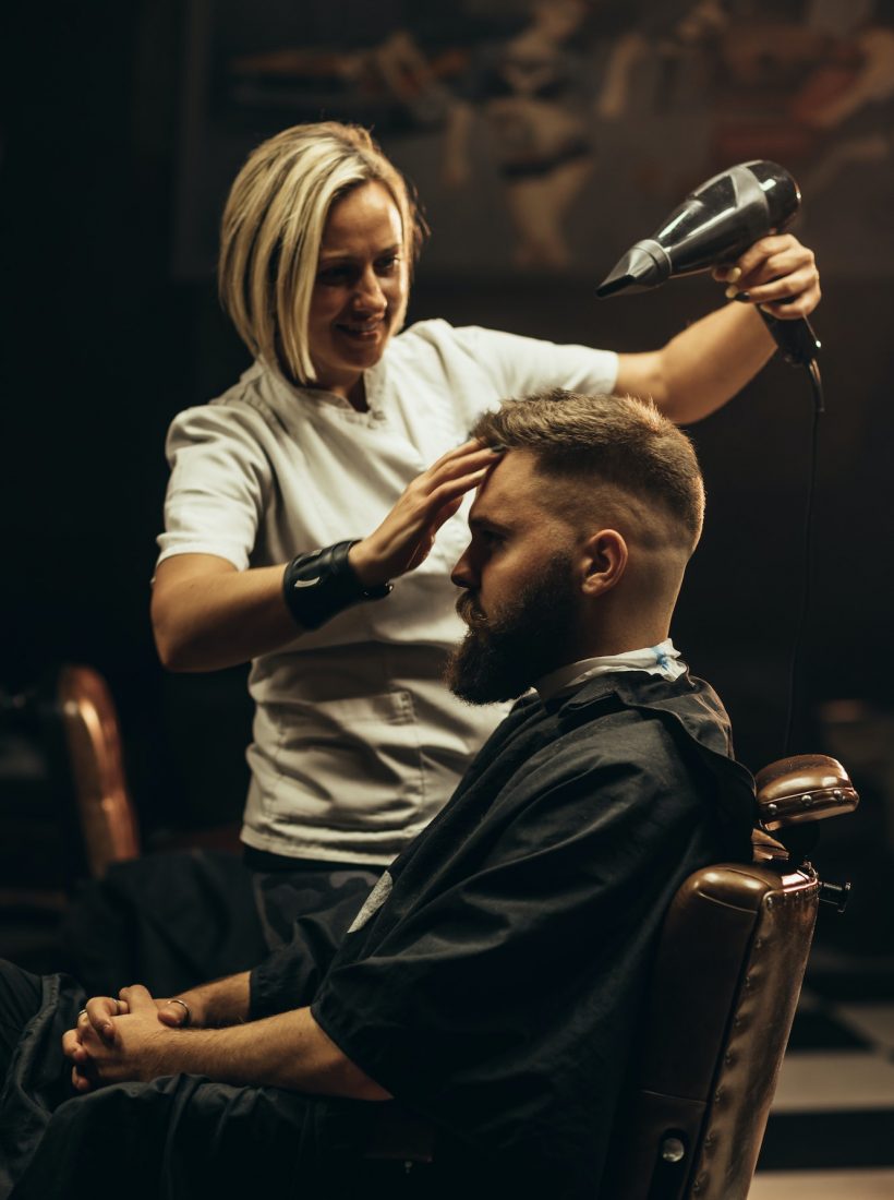 Young bearded man getting haircut by hairdresser