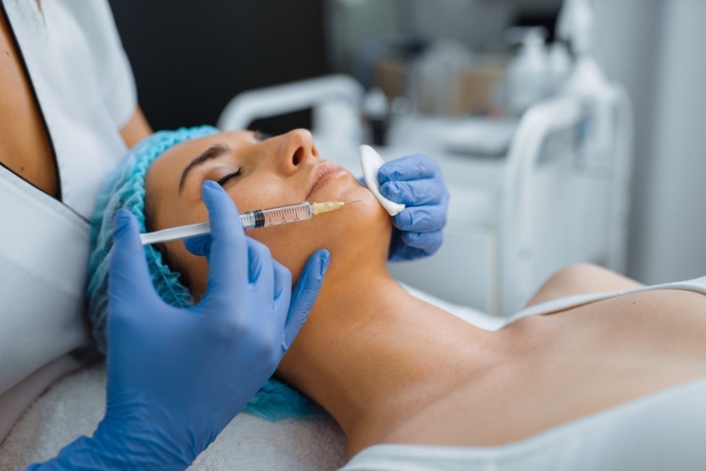 Cosmetician gives chin botox injection to patient