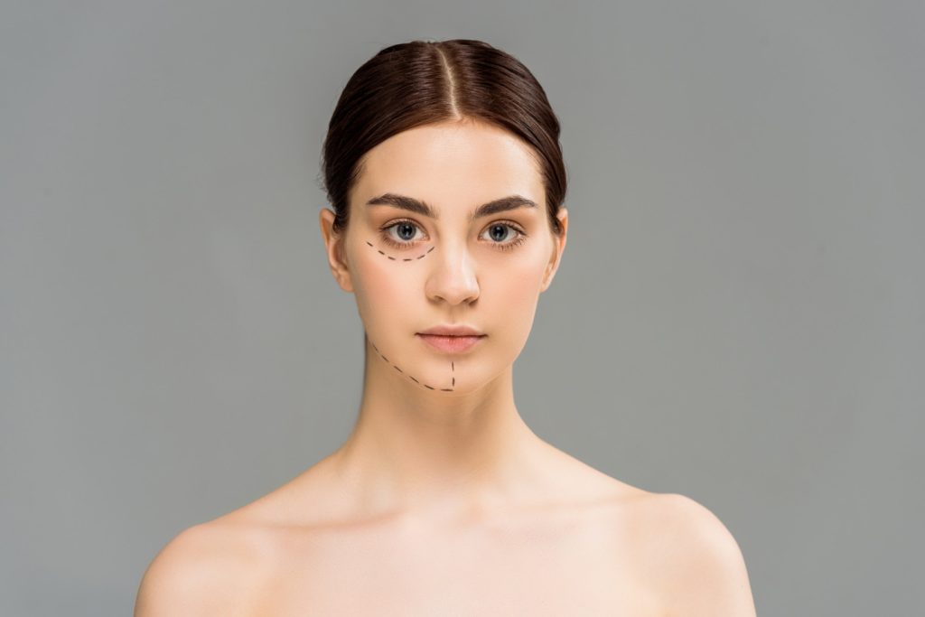 pretty young woman with marks on face looking at camera isolated on grey