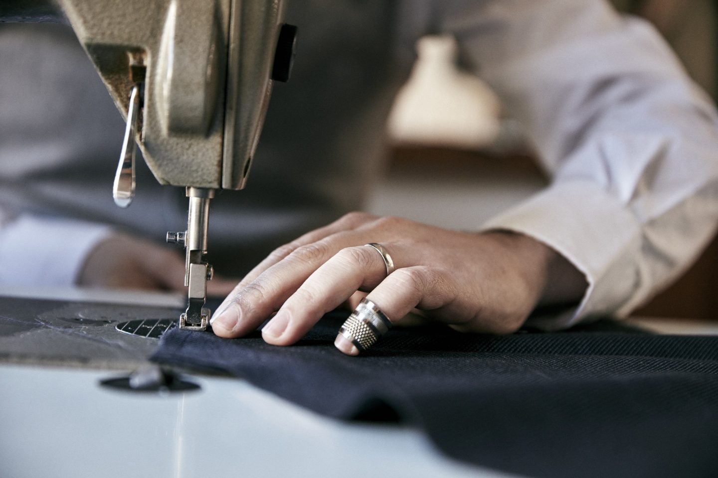 Man using an industrial sewing machine, stitching a garment.