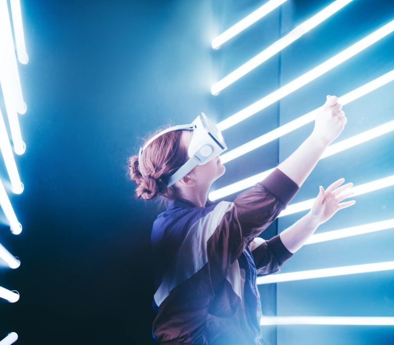 Girl using VR goggles in colorful neon lights